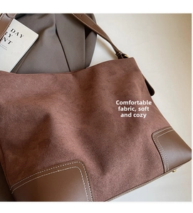 Close-up of vintage brown suede tote with white contrast stitching and leather corner patch