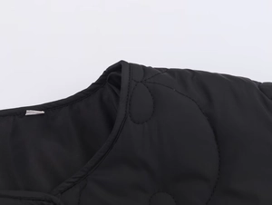 Gros plan détaillé d'une veste matelassée noire avec motif floral et encolure ronde
