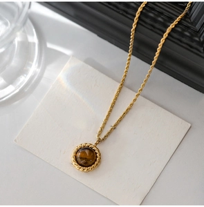 Detail of gold twist chain necklace with round brown tiger eye stone pendant on card