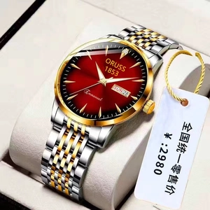Macro detail of men's steel watch with sunburst red dial and double calendar display