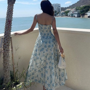 Vue arrière d'une robe d'été à fleurs bleues et blanches sur un balcon vue mer