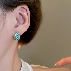 Close-up of elegant square light blue gemstone earrings with gold finish on model