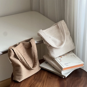 Detailed view of beige and cream herringbone texture on woven shoulder tote bags