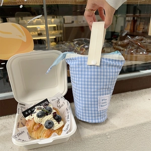 Blue gingham canvas tote bag with cream handles shown in a cafe bakery setting