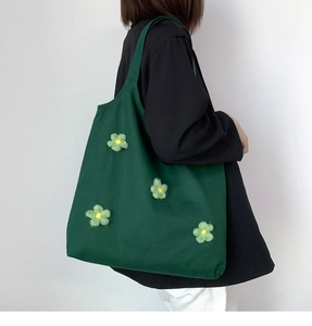 Detail of green canvas tote bag featuring unique 3D knit floral decorations for women