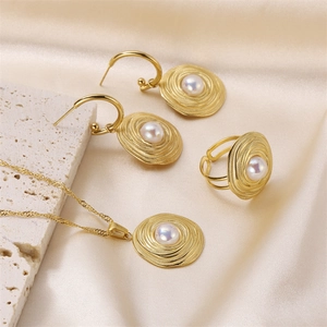 Elegant gold jewelry set with concentric textures and pearls on silk and stone base