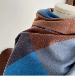 Macro shot of plaid cashmere-like scarf showing blue and brown knit texture details