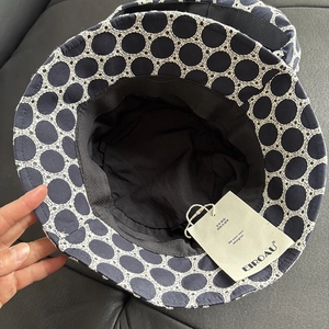 Close-up of navy blue bucket hat with white ring embroidery and black inner lining
