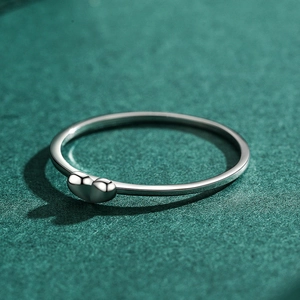 Minimalist 925 sterling silver heart ring with polished finish on a dark green surface