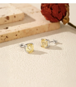 Detail of S925 sterling silver studs with round yellow gemstone on a stone surface