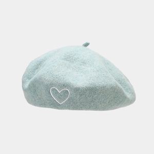Macro detail of wool blend light blue beret featuring delicate white heart embroidery