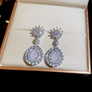 Gros plan de boucles d'oreilles fleurs en zircon avec pierre lavande dans un écrin