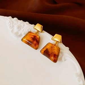 Retro amber resin trapezoid earrings with gold plating on white decorative tray