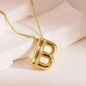 Macro shot of 18K gold balloon letter B pendant with shiny metallic finish on bead chain