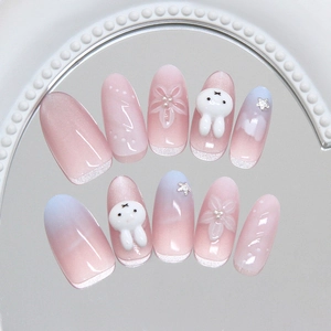 Pink and blue cat-eye press-on nails with 3D bunny and flower charms on a mirror