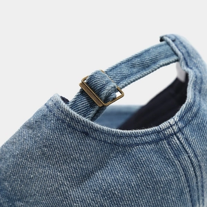 Detail of blue denim baseball cap with adjustable antique bronze metal buckle closure
