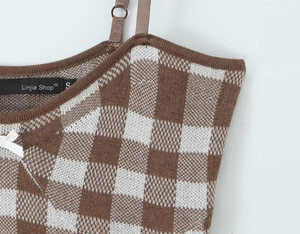 Details eines karierten Strickkleides mit weißer Schleife und schmalen Trägern