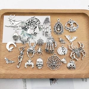 Flat lay of vintage silver Halloween charms like pumpkins and skulls on a wooden tray