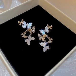 Detailed close-up of silver butterfly tassel earrings with zircon and shell inlay