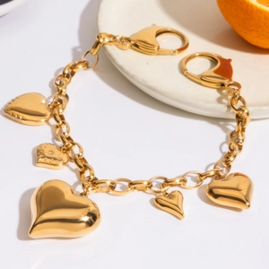 Detail of 18K gold-plated heart charms and star-engraved pendants on a metal chain
