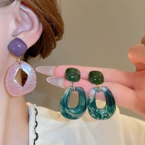 Detailed close-up of handmade resin geometric earrings with marble texture and wood accents