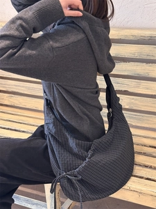 Macro detail of dark grey grid pattern hobo bag showing drawstring and metal zipper side