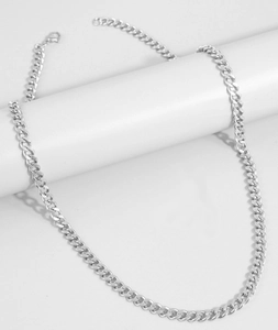 Detailed view of silver Cuban link chain draped on a white column with metallic luster