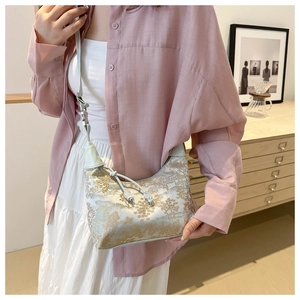 Detail of vintage silk handbag featuring golden embroidery and elegant tassel drawstring