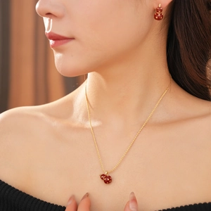 Close-up of 18k gold plated necklace and earrings set with red gourd pendants on a model