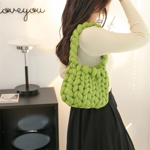 Handmade green chunky knit bag with thick yarn texture shown on a stylish model