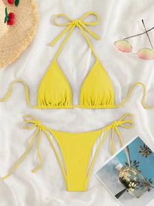 Detailed flat lay of a yellow textured bikini with halter top and side-tie bottoms