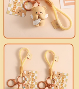 Detail of Cream Bear keychain with white wings, woven strap and branded metal tag