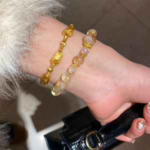 Detail of layered gold beaded bracelet and translucent yellow crystal bead bracelet