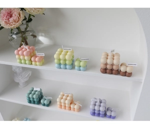 Close-up of colorful handmade cube bubble candles on a white display shelf