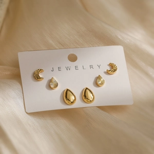 Three pairs of 18K gold plated heart and geometric stud earrings set on a white jewelry card