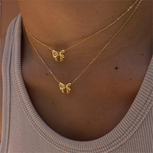 Elegant gold double-layered necklace with bow pendants worn by a model on collarbone