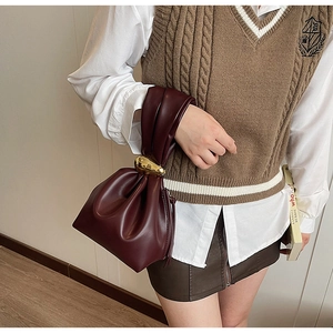 Detail of dark red pleated bucket bag with gold metal buckle and soft leather texture