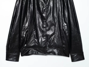 Detail of black leather bomber jacket featuring stitch lines and elastic hem pockets