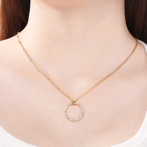Dettaglio della collana con ciondolo circolare dorato e strass pavé su un modello di collo