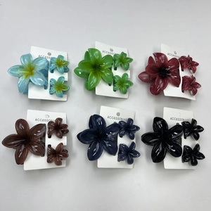 Flat lay set of colorful plumeria flower hair claws in six vibrant summer shades