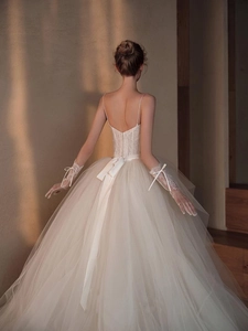 Detail of elegant white lace wedding dress featuring backless V-neck and silk ribbon bow