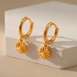 Detail of 18K gold-plated huggie hoop earrings with radiant sunburst flower pendants