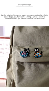 Detail of cartoon black cat enamel pins with floral motifs on a green canvas bag