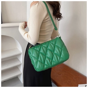 Detail showing green quilted crossbody bag with gold chain strap worn by a model
