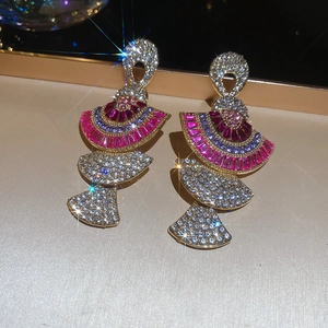 Macro shot of luxurious fan-shaped gold earrings with pink gemstones and sparkling crystals