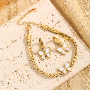 Elegant gold butterfly jewelry set featuring a bracelet and earrings on stone background