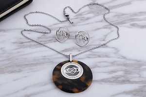 Close-up of leopard print pendant and stainless steel infinity heart jewelry set on marble