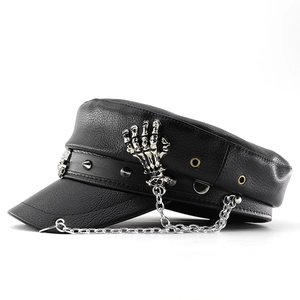 Detail of flat top army cap featuring silver metal skull hand, chain, and cone studs