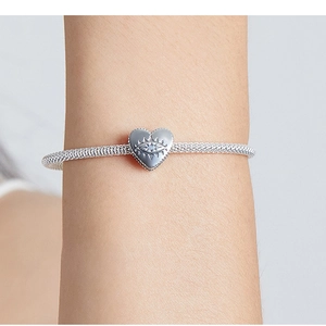 Macro shot of silver heart charm with evil eye design and gemstone on a bracelet
