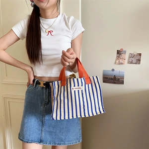 Detail of blue and white striped knit tote bag with orange handle and brand tag